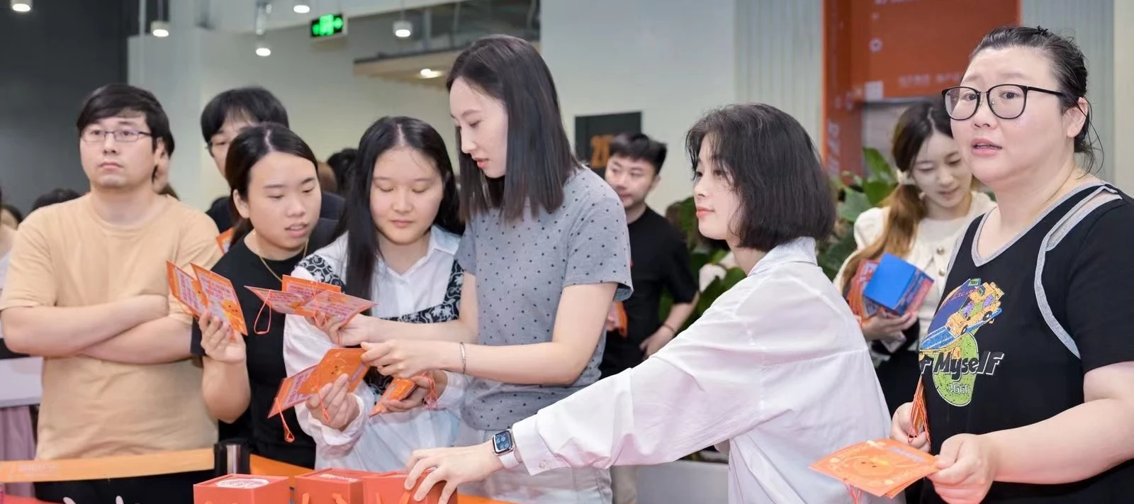 Colleagues from the Customer Operations team at an Alibaba event, handing out orange cards and gift boxes at a table.
