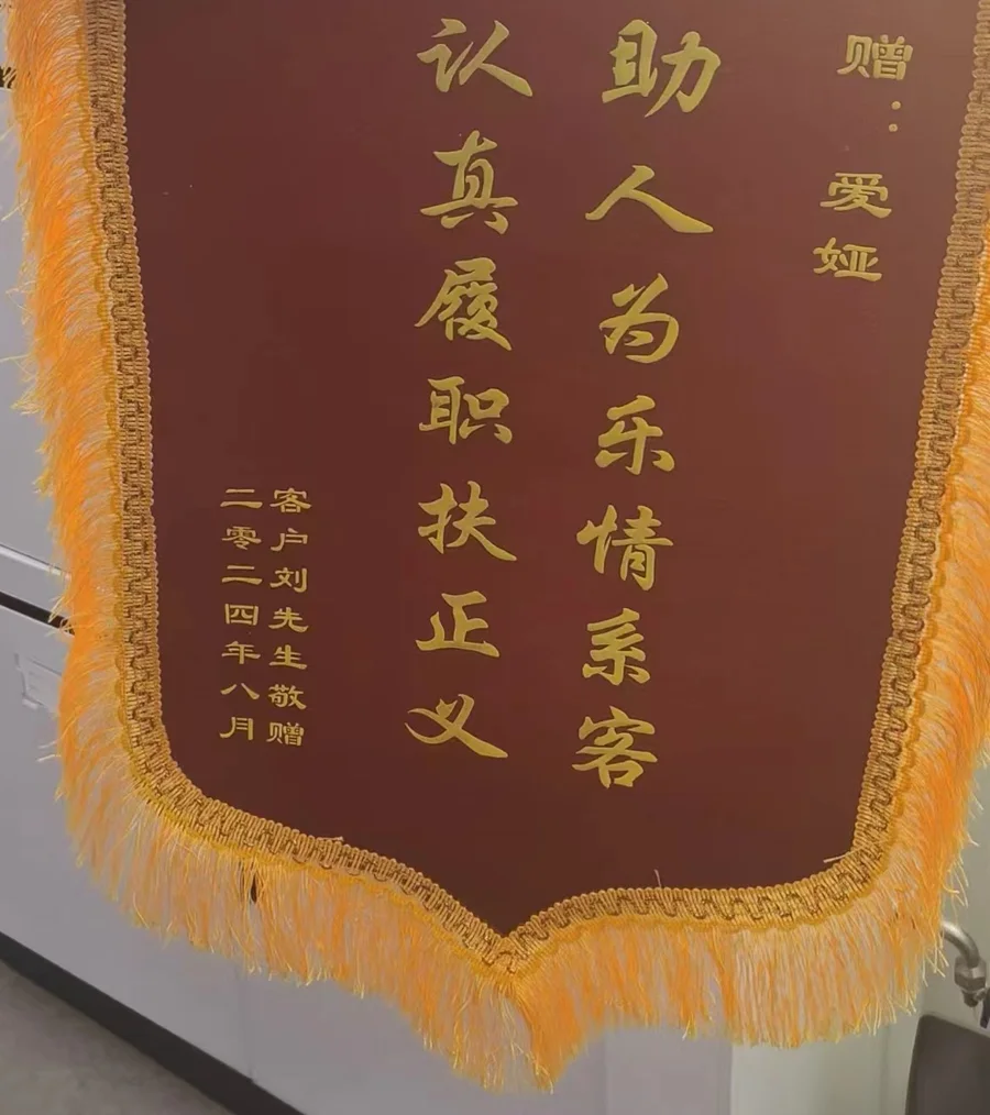 A red silk thank-you banner with gold fringe and gold Chinese characters, given by a customer in August 2024.